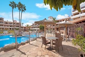 a resort with a pool and a table with chairs and umbrellas at Cathamarcella in San Miguel de Abona