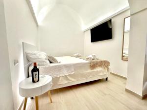 Un dormitorio blanco con una cama y una botella de vino sobre una mesa. en La Casa di Ninetta - Boutique Stay, en Monopoli