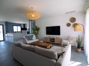 a living room with a couch and a tv at Villa de l'Ile d'Olonne in LʼÎle-dʼOlonne