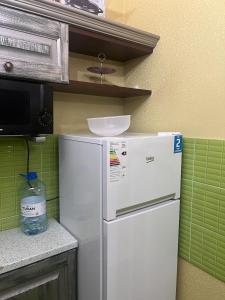 einen weißen Kühlschrank in einer Küche mit grünen Fliesen in der Unterkunft 38 Теплые апартаменты с 2 кроваями у Байтерека in Zhezdi