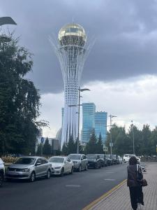 Eine Frau, die eine Straße entlang geht, neben einem Parkplatz in der Unterkunft 38 Теплые апартаменты с 2 кроваями у Байтерека in Zhezdi