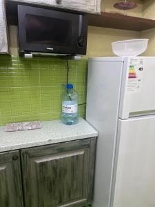 eine Flasche Wasser auf einer Theke neben einem Kühlschrank in der Unterkunft 38 Теплые апартаменты с 2 кроваями у Байтерека in Zhezdi