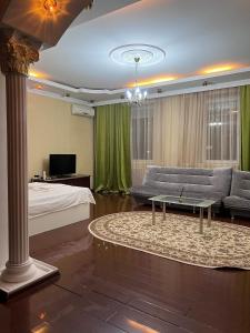 ein Zimmer mit einem Bett, einer Couch und einem Tisch in der Unterkunft 38 Теплые апартаменты с 2 кроваями у Байтерека in Zhezdi