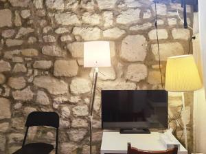a living room with a tv and a stone wall at Cute Marais Studio near Metro Heart of Paris N4-22 in Paris +4 photos