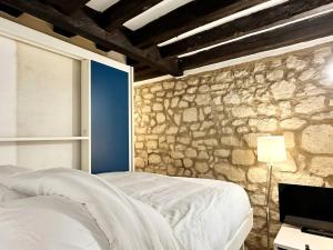 a bedroom with a bed and a stone wall at Cute Marais Studio near Metro Heart of Paris N4-22 in Paris