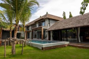 a house with a swimming pool in front of it at Kalamari Luxury Beach Front Villa in Mae Nam