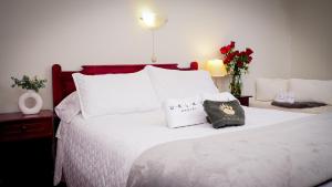 a white bed with white pillows and flowers on it at Ukuku Hostel & Rooftop - Quito in Quito