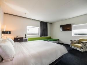 a bedroom with a large white bed and a chair at Tulip Inn Eindhoven Airport in Eindhoven +41 photos