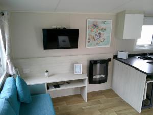 a living room with a blue couch and a tv on the wall at Seaview Moonstone Deluxe 6 Berth central heated FREE WIFI in Ingoldmells
