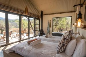a bedroom with two white beds and a large window at Sasi Bush Lodge- Exclusive Use Luxury Tented Safari Lodge in Bergville