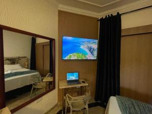 a hotel room with a bed and a laptop on a desk at Belíssimo Estudio Stella Maris in Andradina