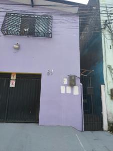 a white building with a black gate and a garage at suíte feliz in Belém
