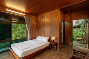 a bedroom with a bed and a large window at Chezbeo Bungalow Ninh Binh in Vũ Lâm