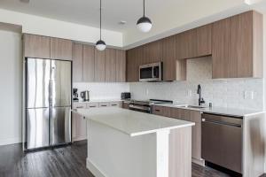 a kitchen with wooden cabinets and a stainless steel refrigerator at Blueground Lynnwood view nr Lynndale Park SEA-950 in Lynnwood