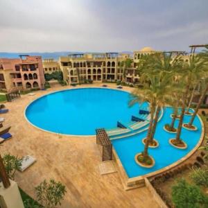 a large blue swimming pool with palm trees and buildings at منتجع تالابيه العقبة in Aqaba