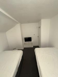 Habitación pequeña con 2 camas y TV. en WOLVES Stay, en Wolverhampton