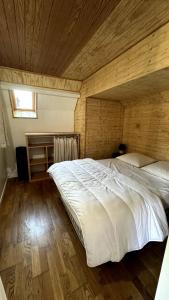 a large white bed in a room with a wooden ceiling at Chalet Le Capéna Lac de Payolle in Campan +4 photos