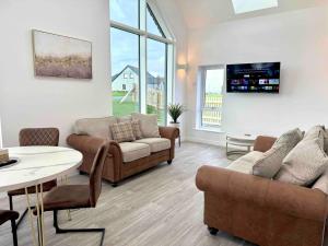 un salon avec des canapés, une table et une télévision dans l'établissement Isles View, Luxury Modern Spacious Villa in Kirkwall, à Orkney