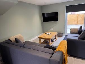 a living room with a blue couch and a tv at Oakwood Farm Barns in Chester