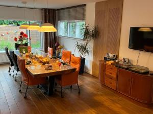 a dining room with a table with chairs and a television at Bed&Breakfast Maasland in Maasland