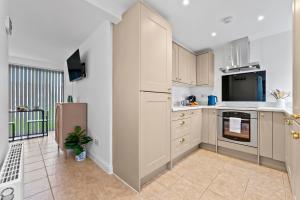 Una cocina con gabinetes blancos y un refrigerador. en Near Warwick Hospital, Cozy Studio, Free Parking, en Warwick