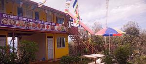 ThapathaliにあるEverest Home Stay Temal Kalimati Towerの看板とテーブルと傘のある建物