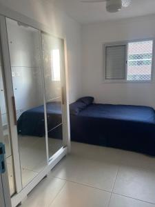 a bedroom with a bed and a glass closet at Apartamento frente á praia - vista incrível e conforto in Praia Grande