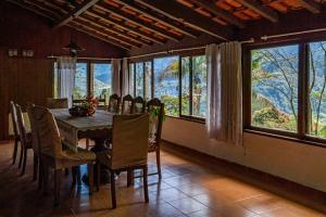 uma sala de jantar com mesa, cadeiras e janelas em Refúgio na Serra de Petrópolis simples e acolhedor em Petrópolis