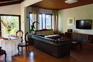 uma sala de estar com um sofá de couro e uma mesa em Refúgio na Serra de Petrópolis simples e acolhedor em Petrópolis
