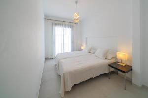 a white bedroom with a bed and a side table at Ático con gran terraza privada cerca de la playa in Nerja