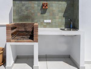 a kitchen with a sink and a brick oven at Ático con gran terraza privada cerca de la playa in Nerja +8 photos