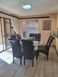 a dining room with a glass table and chairs at Papillon Guesthouse in Johannesburg