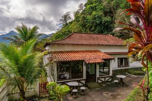 uma pequena casa com uma mesa e cadeiras em frente em Refúgio na Serra de Petrópolis simples e acolhedor em Petrópolis