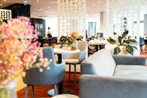 a restaurant with couches and tables and flowers at Focus Hotel Premium Gdańsk in Gdańsk