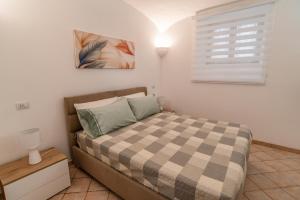a bedroom with a bed with a checkered blanket at Apartment Sole e Luna - Fronte Mare in Nettuno