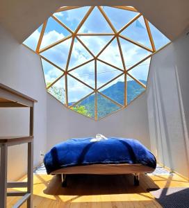 ein großes Fenster in einem Zimmer mit einem blauen Kissen in der Unterkunft Fuji Dome Glamping in Fujikawaguchiko