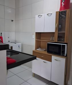 a kitchen with white cabinets and a microwave on a counter at Apartamento acolhedor Maracanaú -Premium in Maracanaú