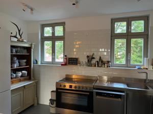 a kitchen with a stove and a sink and two windows at Forsthaus Barsdorf in Fürstenberg