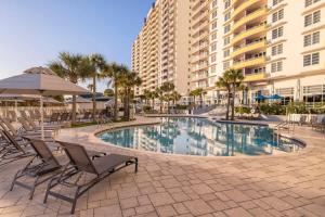 a pool with chairs and umbrellas next to a building at Wyndham Ocean Walk Resort 2BR Apartment with Resort Access in Seabreeze