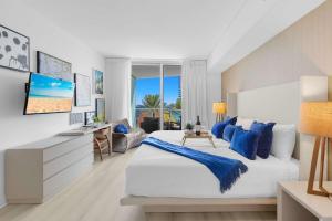 a white bedroom with a large bed with blue pillows at Rooftop Pool Oceanview Balcony & Beachfront Resort in Hollywood Beach