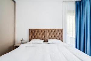 a bedroom with a large bed with blue curtains at Status-M Apartments 187 in Becici +25 photos