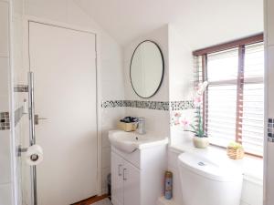 a white bathroom with a toilet and a mirror at Periwinkle Cottage in Conwy +27 photos