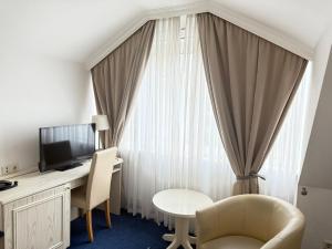 una habitación con un escritorio con televisión y una mesa en HOTEL S Norderstedt, en Norderstedt