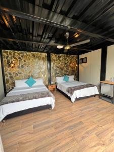 a bedroom with two beds and a stone wall at Persea Hospedaje in Armenia +18 photos