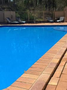 a blue swimming pool with chairs and a table at Tranquil Queen Room & Pool in Upper Mudgeeraba
