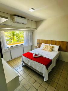 une chambre avec un lit avec une couverture rouge et une fenêtre dans l'établissement Flat Completo - Praia de Jatiuca, à Maceió