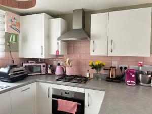 cocina con armarios blancos y azulejos rosados en Pink Paradise, en Dunstable 2 fotos más