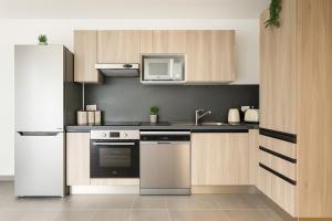 eine Küche mit Holzschränken und einem weißen Kühlschrank in der Unterkunft Spacieux 3 chambres et lumineux à Montrouge in Malakoff + 16 Fotos