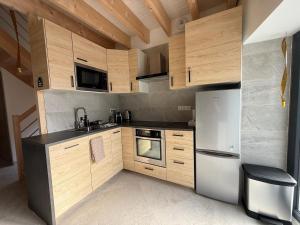 eine Küche mit Holzschränken und einem Edelstahlkühlschrank in der Unterkunft Charmante maison rénovée avec terrasse et jardin in Crillat