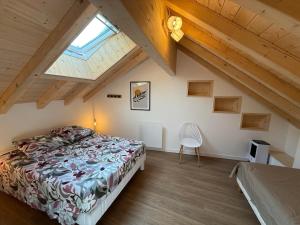 Schlafzimmer im Dachgeschoss mit einem Bett und einem Fenster in der Unterkunft Charmante maison rénovée avec terrasse et jardin in Crillat